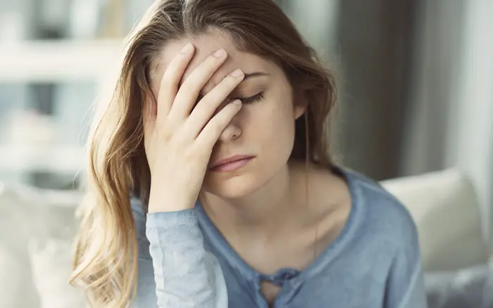 woman in her thirties looking ill, covering her face with her hand - addiction detox