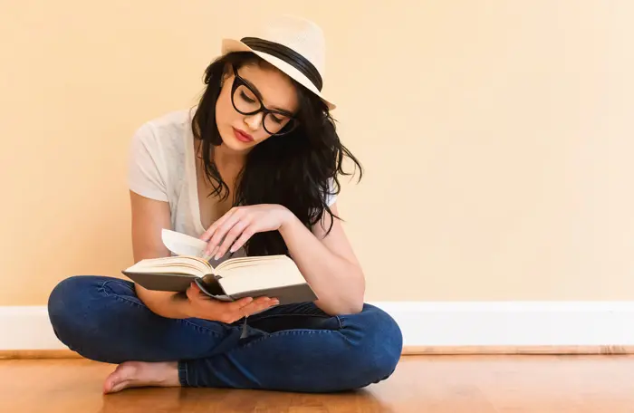 pretty young woman in a fedora sitting cross-legged, and reading a book - movies