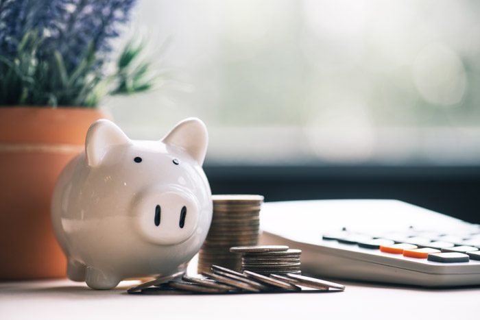 cute piggy bank and change next to a calculator on a home desk - pay for treatment