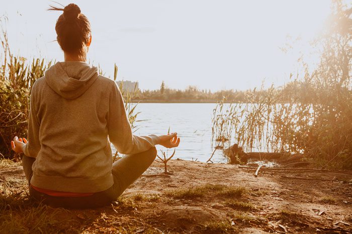 woman facing away from camera, meditating near a lake - meditation